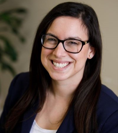 A smiling woman wearing glasses with her hair down.